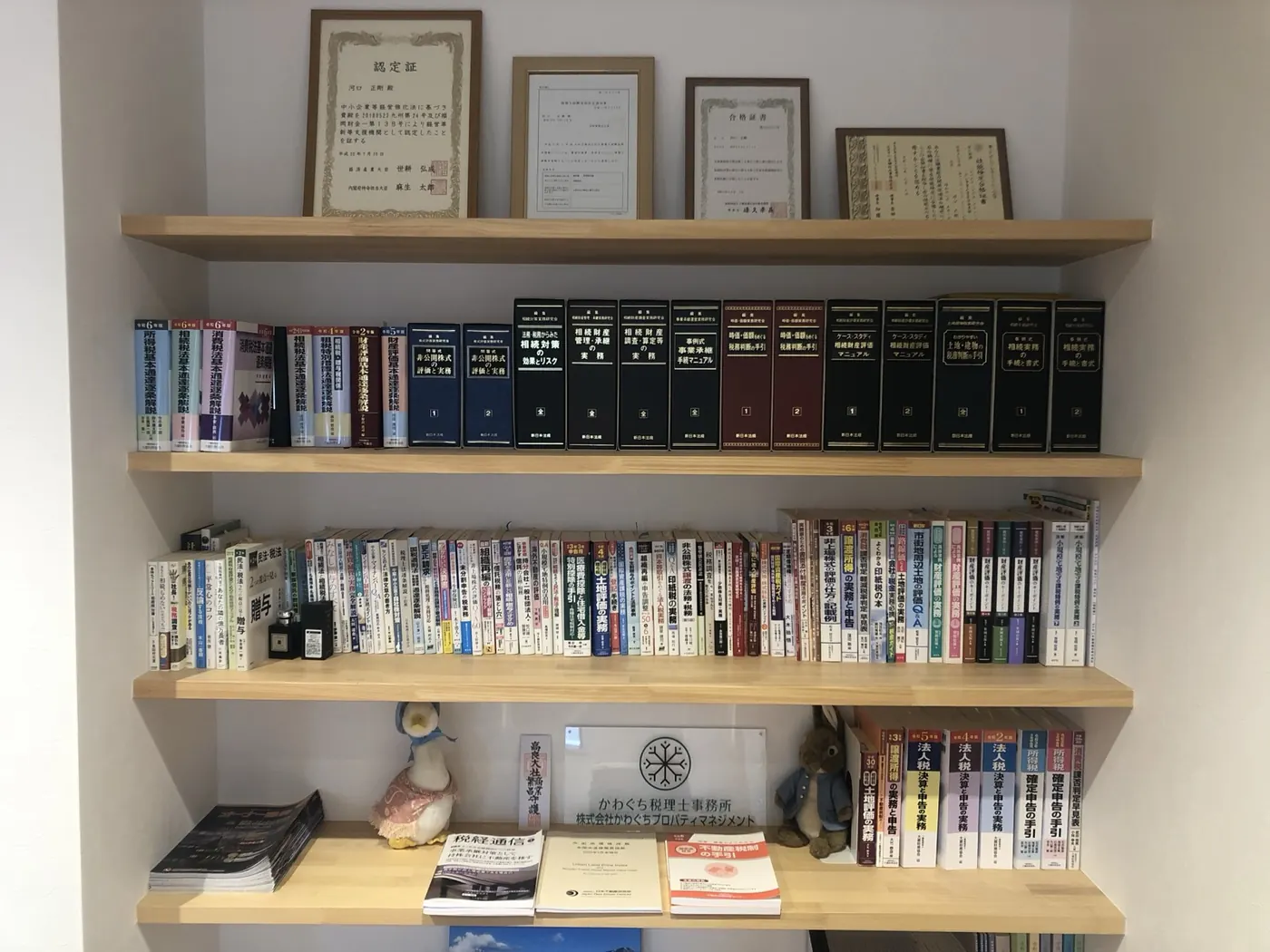 相続の専門書と認定証が並ぶ、かわぐち税理士事務所の書架